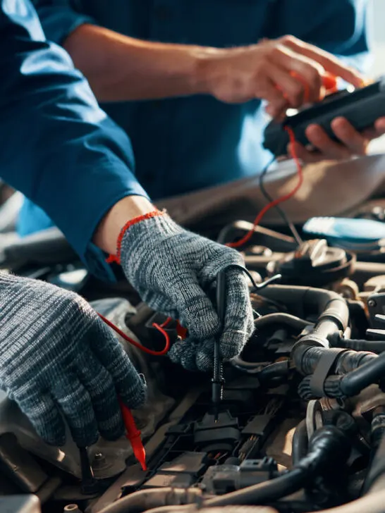 mechanics testing car battery and electrical parts