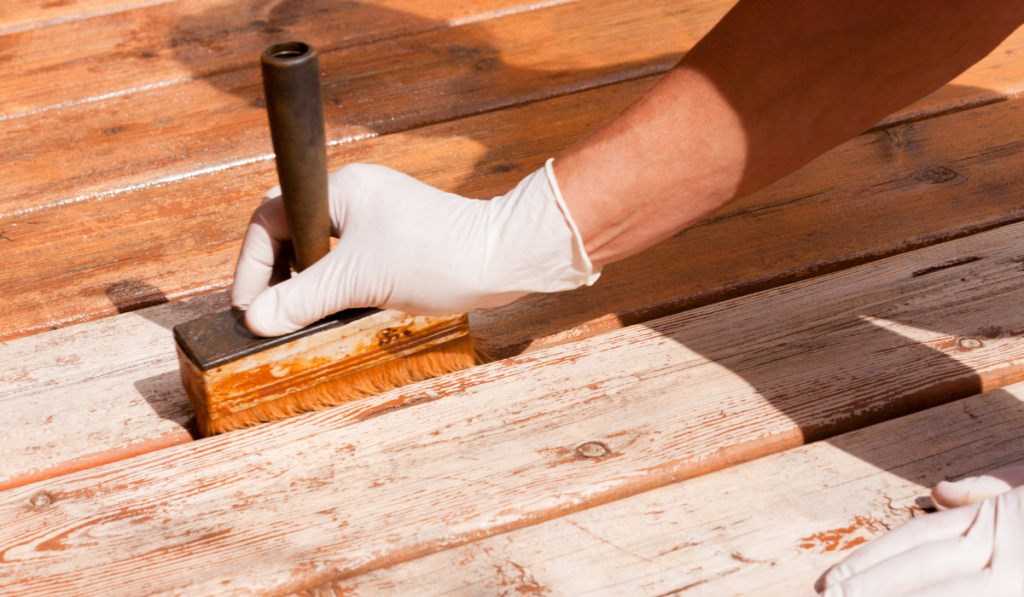 Deck maintenance apply stain on wooden decking
