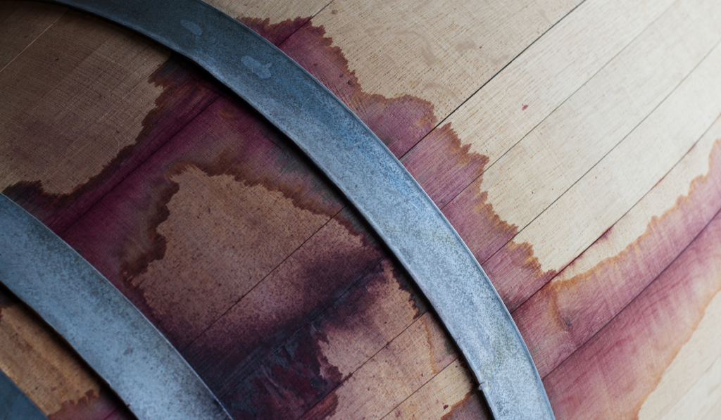 front view closeup of a wine oak wood barrel texture stained with red tannins


