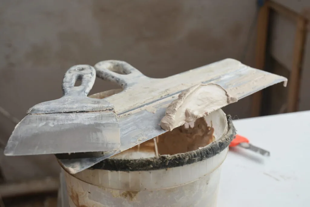 A close-up of working tools of a builder used to spread joint compound, mud, final coats over drywalls