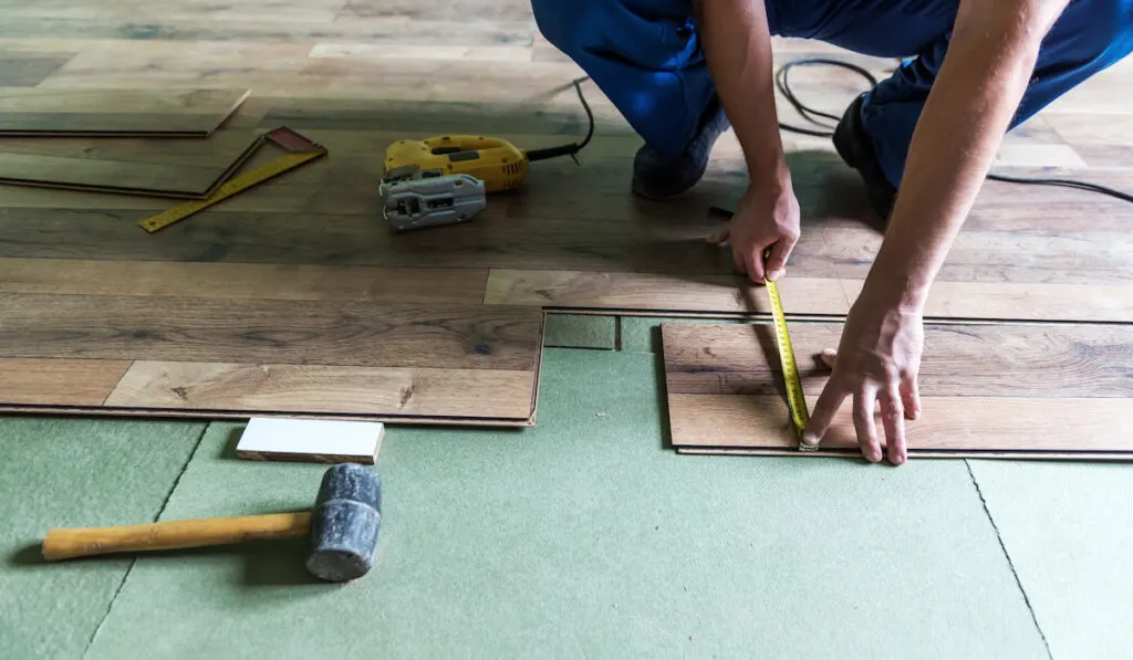 Carpenter installing laminate wood flooring 