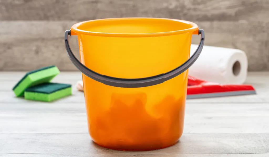 Cleaning bucket orange color on wooden floor background