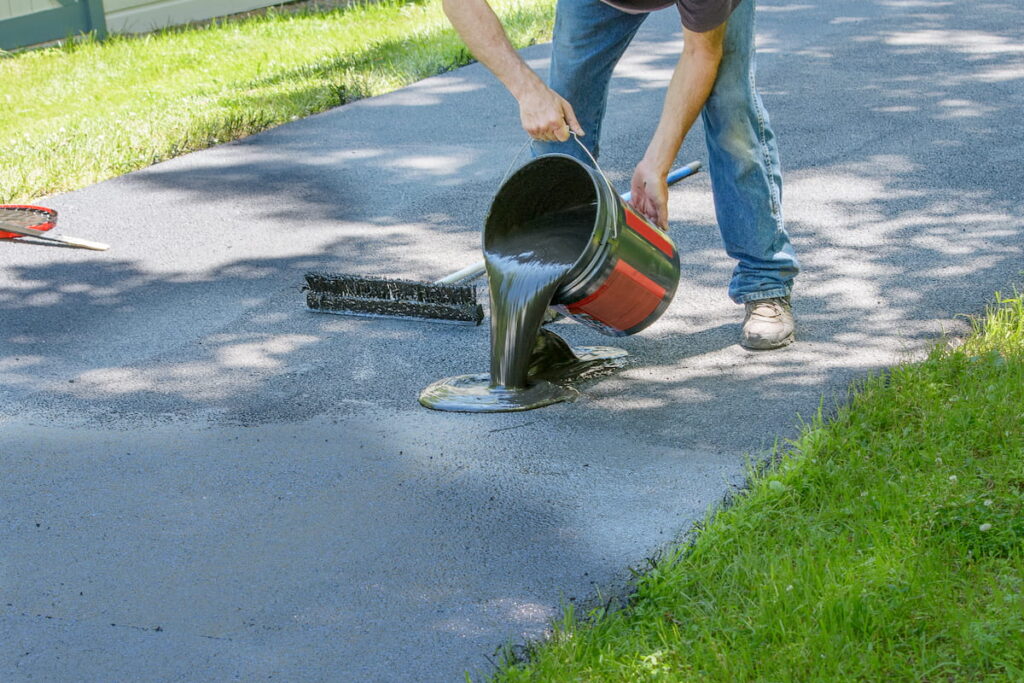 Homeowner pours blacktop sealant onto driveway