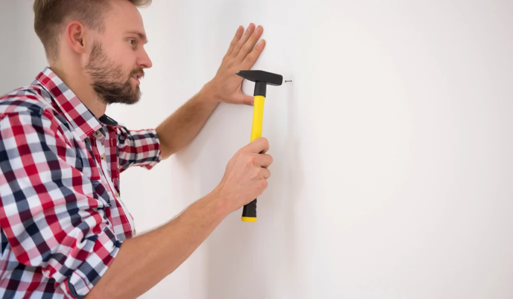 Man hammering a nail into the wall
