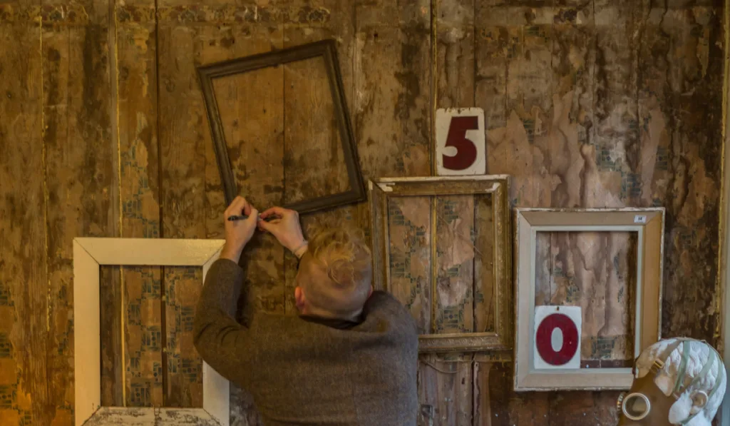 Man nailing frames to wall  