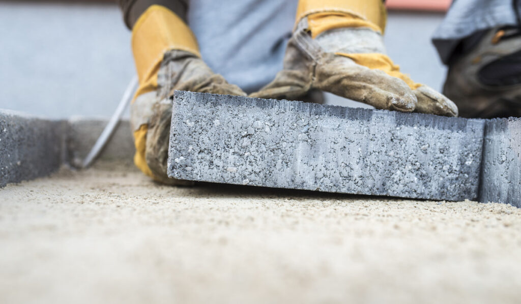 Professional construction worker laying a paving slab