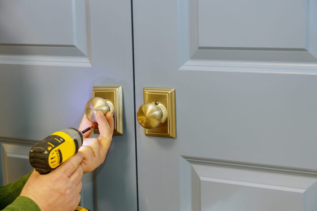 man installing door knob with a screwdriver 