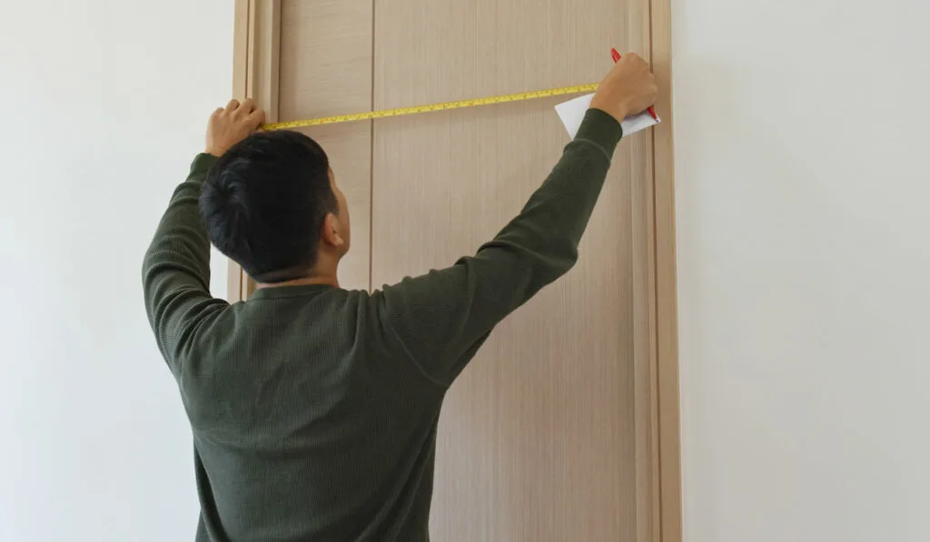 man measuring the door size and write on paper at home