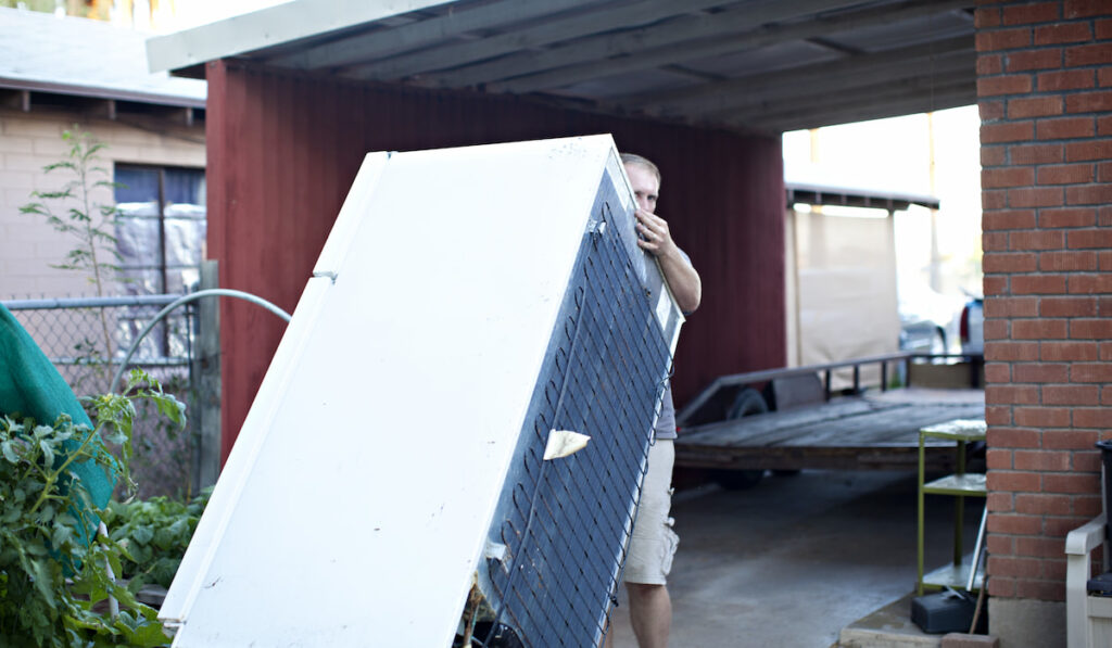 man owner moving refrigerator on his own