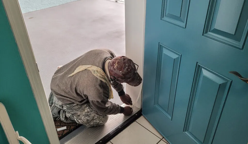worker lining the door frame with rubber condo remodel process 