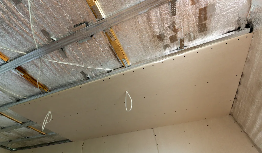 Room under construction with silver aluminum insulation foil and drywall on walls and ceiling