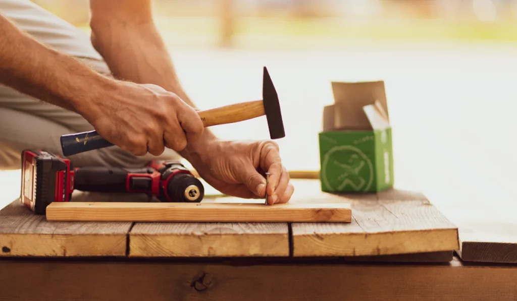 The carpenter hits the nail in the wood