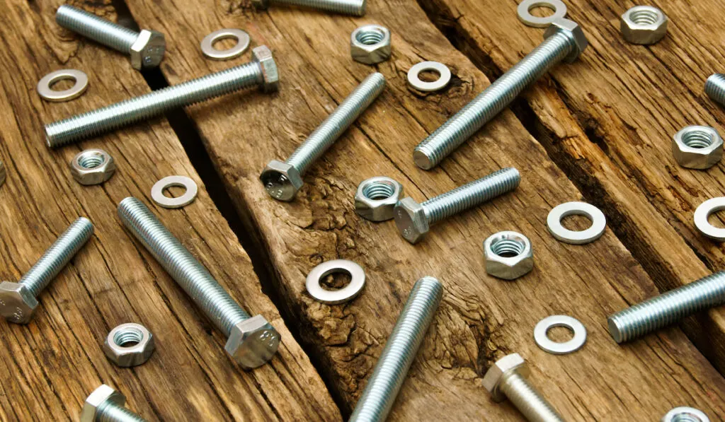hex stainless (nuts, washers, screws) on wooden background.