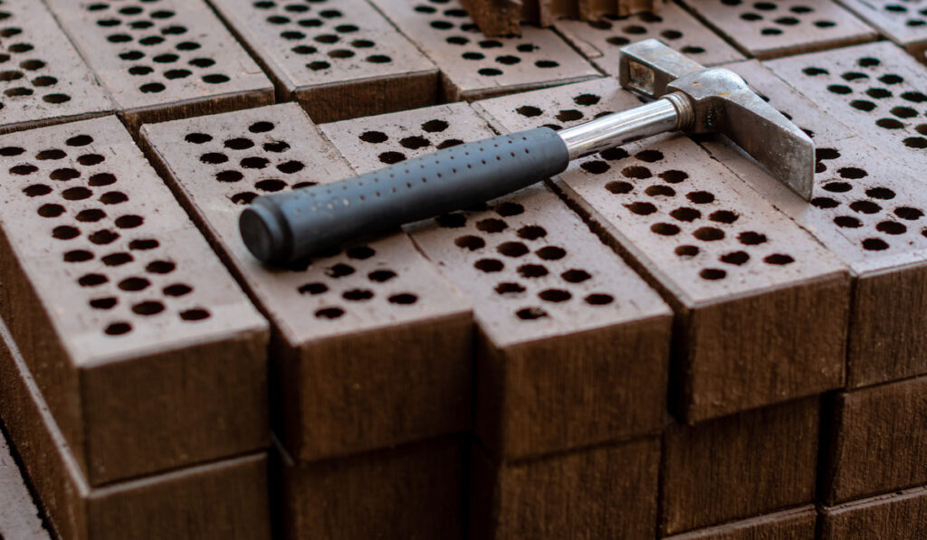 A brick hammer is laid on red brick stack