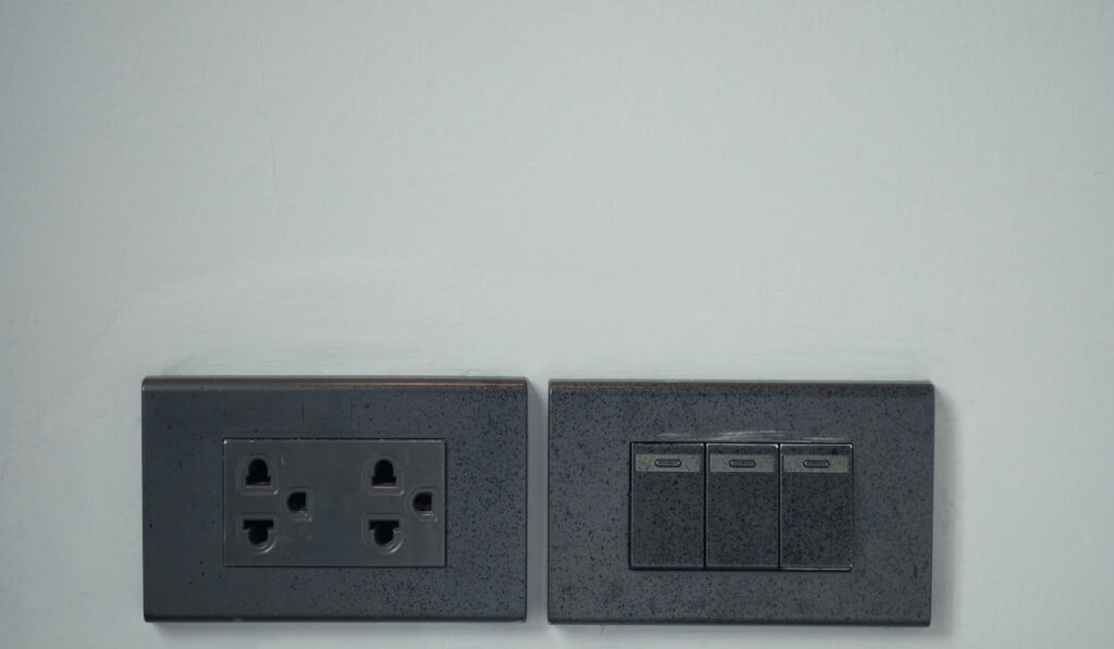 Black colour light switch and outlet plug on the wall at home 