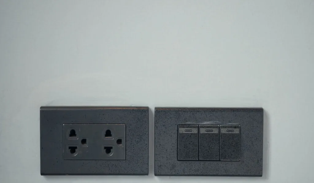 Black colour light switch and outlet plug on the wall at home 
