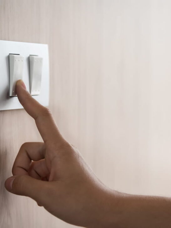 Close-up-of-male-finger-is-turn-on-or-off-on-light-switch-with-wood-wall-at-home