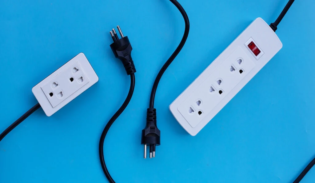 Electrical power strip and plug on blue background.