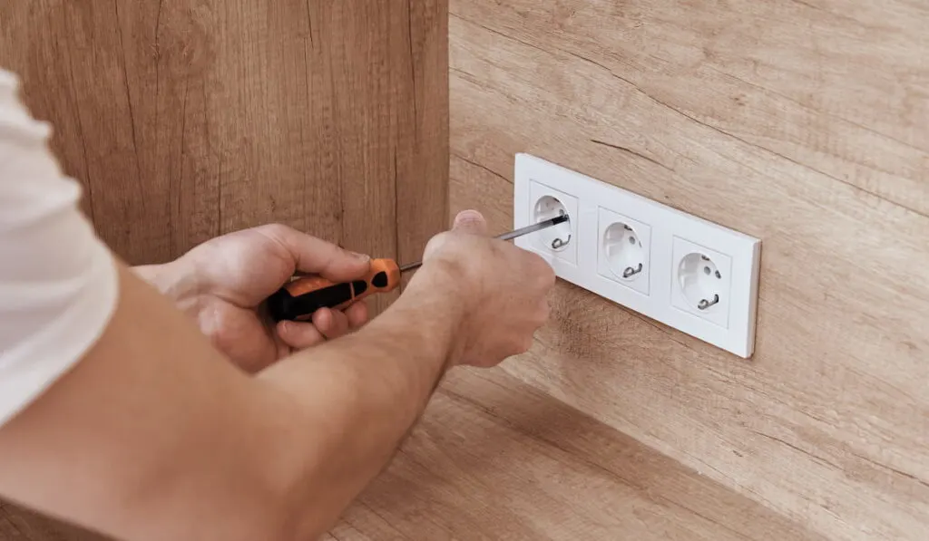 Electrician installing socket in the kitchen