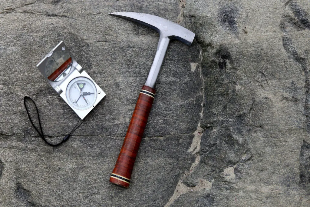 Geologists compass on the stones with rock hammer on the side