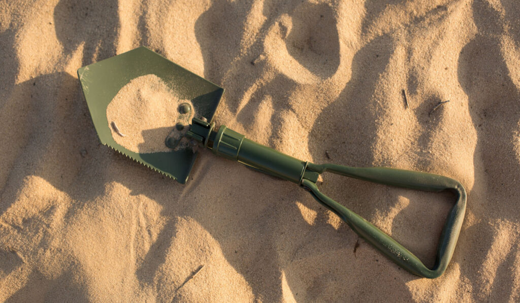 Green Folding shovel in the sand