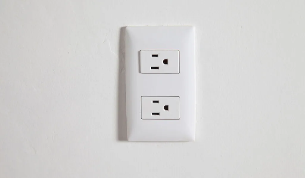 Isolated north american power outlet plug in socket on a white wall background
