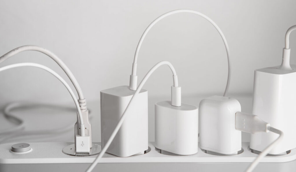 Many chargers plugged into multiple electrical outlet on white background
