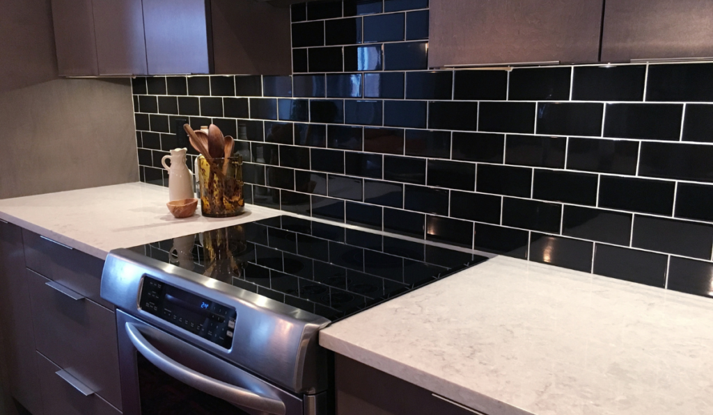 Modern kitchen in dark tones with black tiled wall