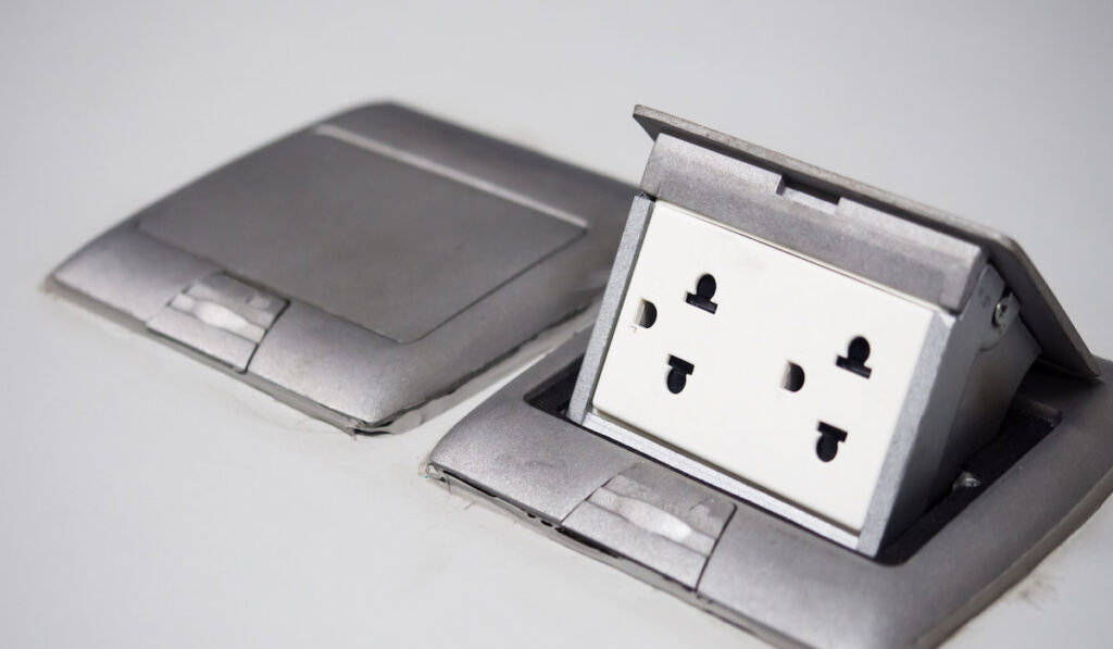 Silver pop up outlet socket on white wall