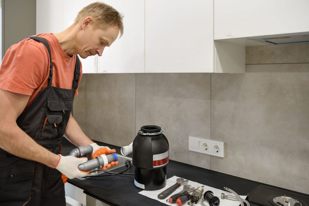 The worker preparing tools to install garbage disposal for kitchen sink