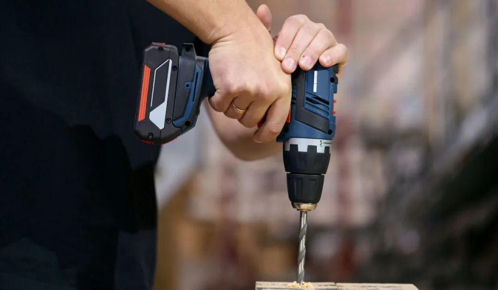hand holding cordless drill drilling wood
