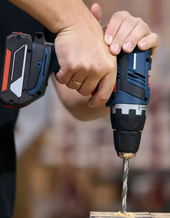 hand-holding-cordless-drill-drilling-wood