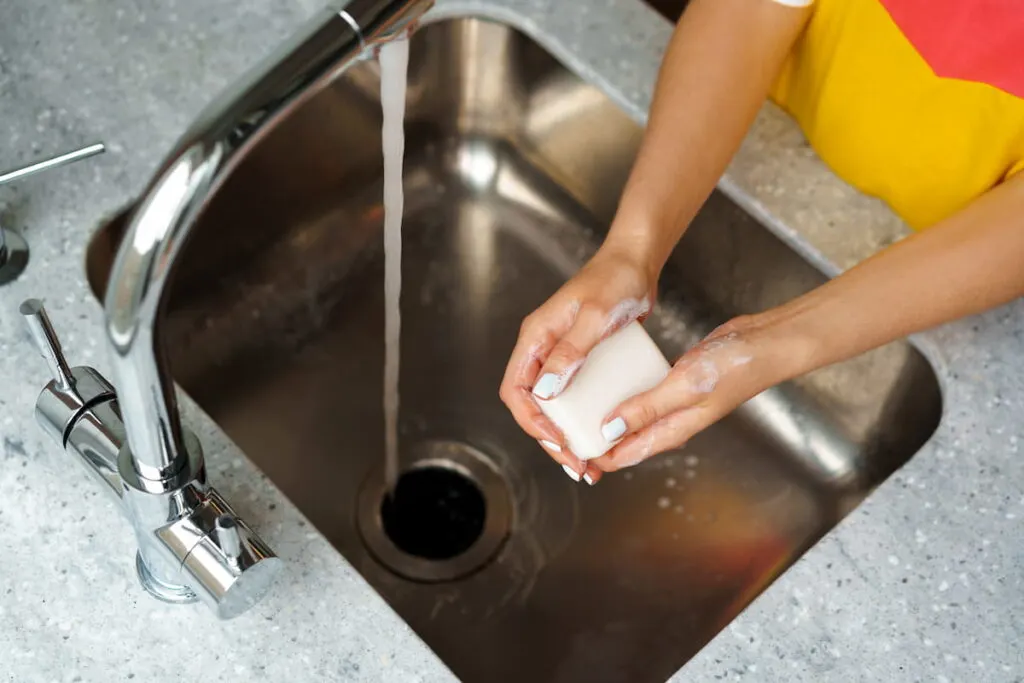 woman washing her hands in a kitchen sink