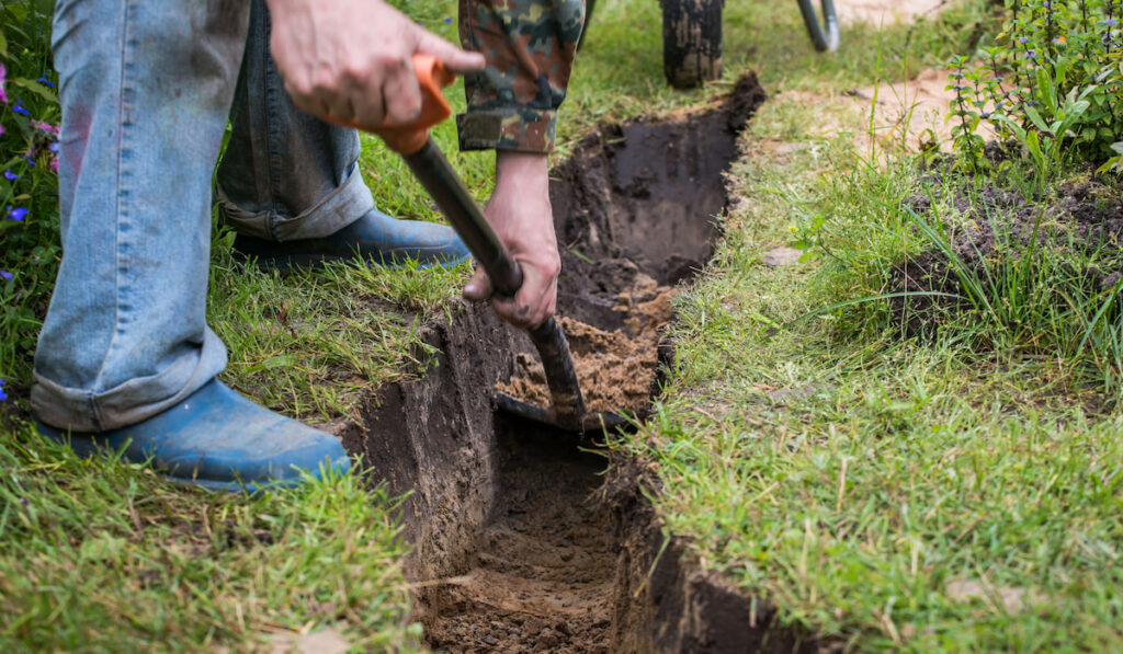 A man is digging a ditch using a shovel