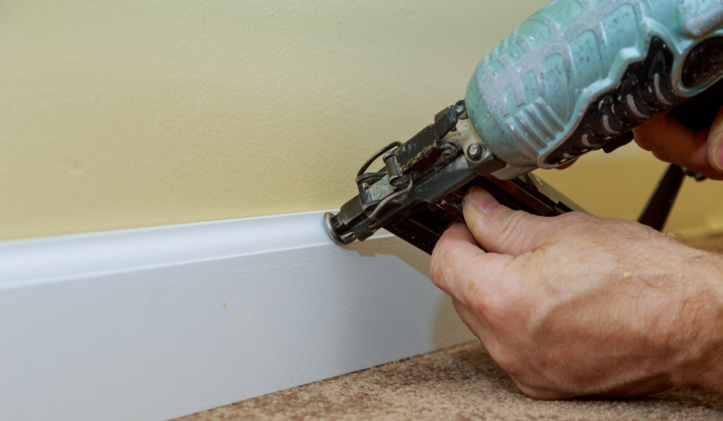 Carpenter install base molding trim air gauge finish nailer man nailed custom house building
