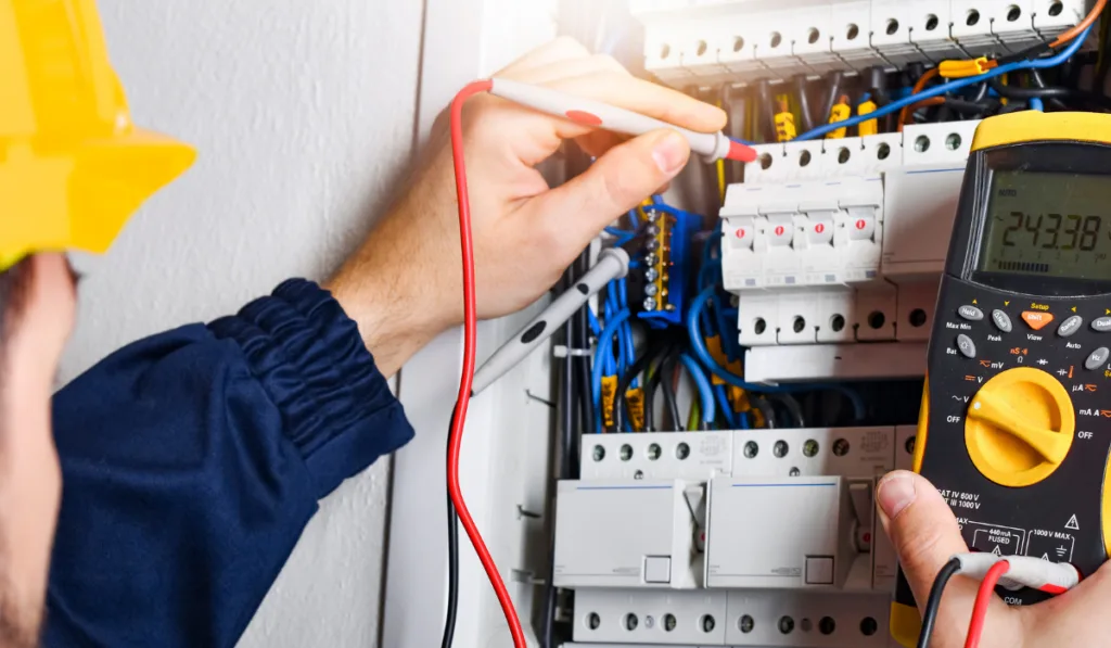 Electrician installing electric cable wires and fuse switch box