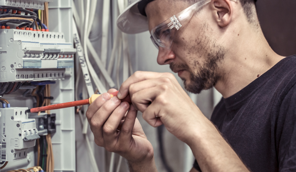 a male electrician works in a switchboard