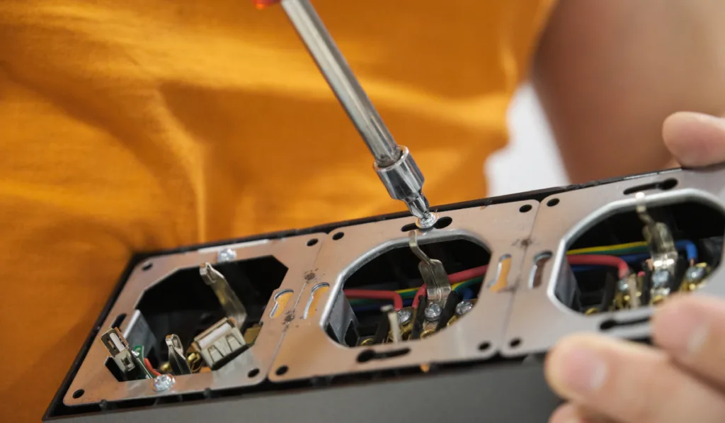 Close up of a man unscrew power socket with screwdriver to install it.
