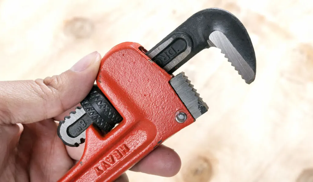 Closeup of a pipe wrench with red handle 