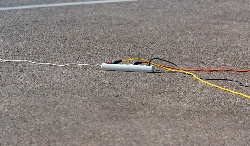 Electric extension cord with wires on the road