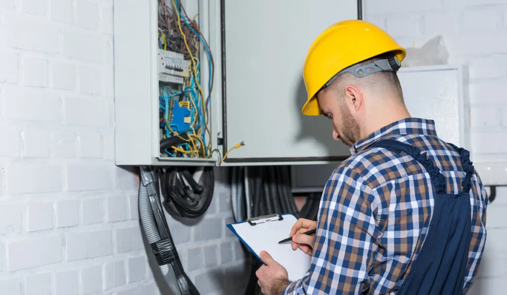 Professional electrician inspecting wires in electrical box