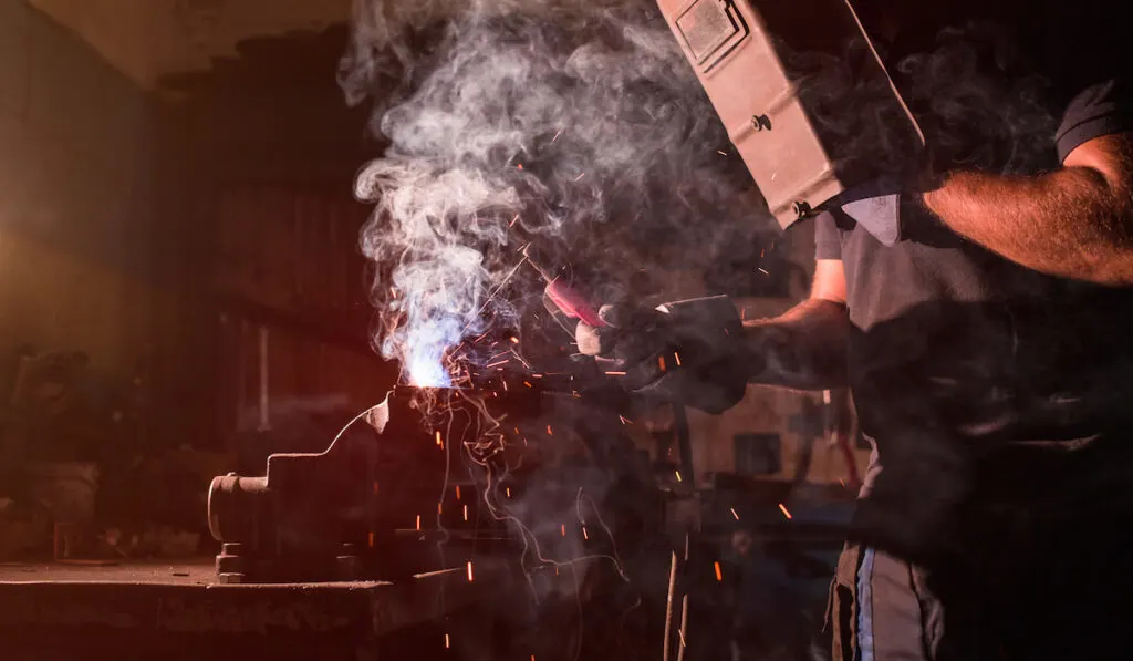 Worker using an oxyacetylene welder in his shop