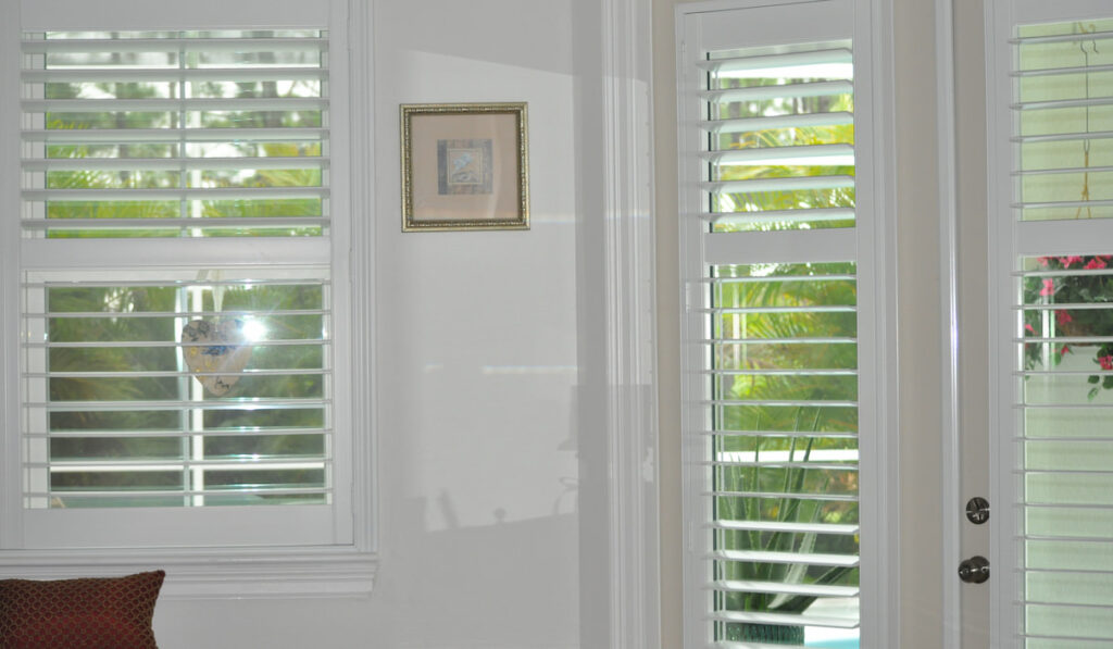 A corner of a room and plantation shutters that are open