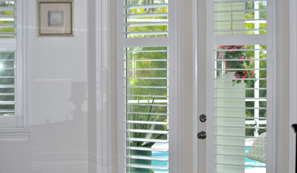 A corner of a room with French doors and plantation shutters 