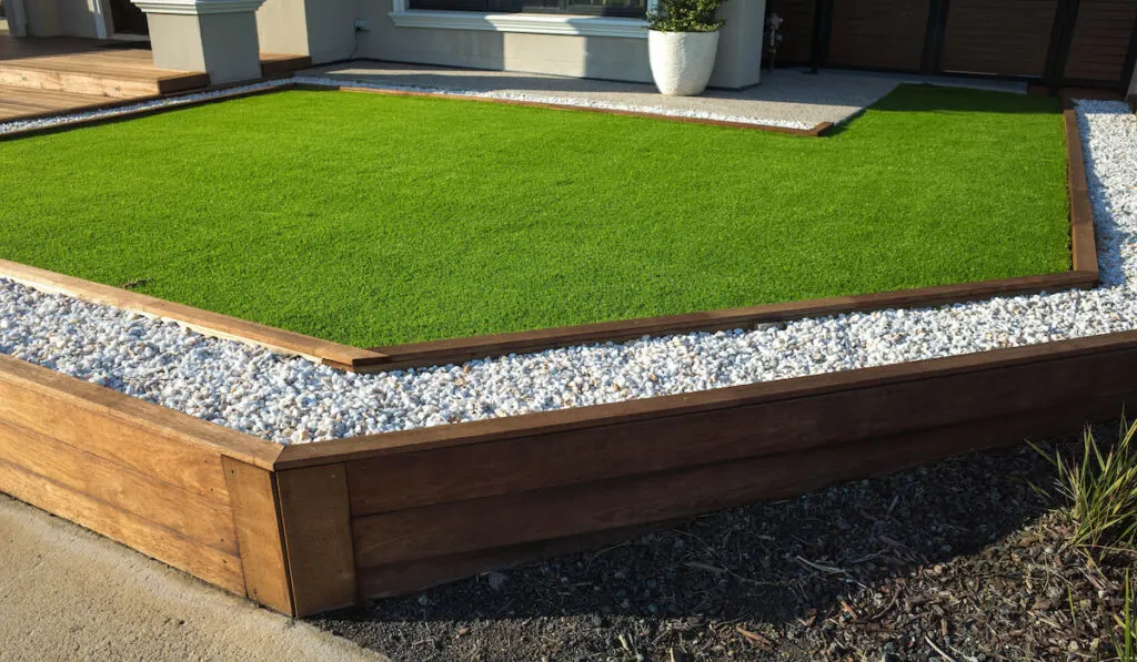 Artificial grass lawn with wooden edging in front yard of a modern house