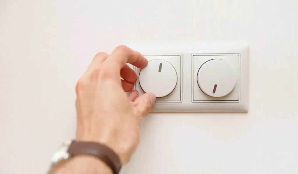 Hand turning down dimmer switch