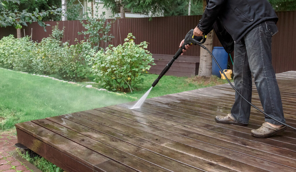 Man cleaning floor with high pressure power washer