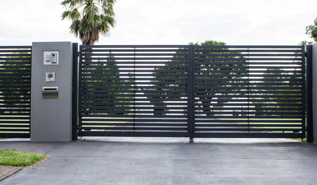 Metal driveway entrance gates in concrete fence