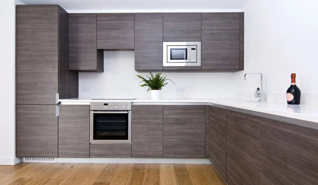 Modern kitchen cabinet in brown with appliances and granite worktops