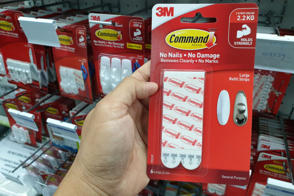 hand holding a package of command strips in a store